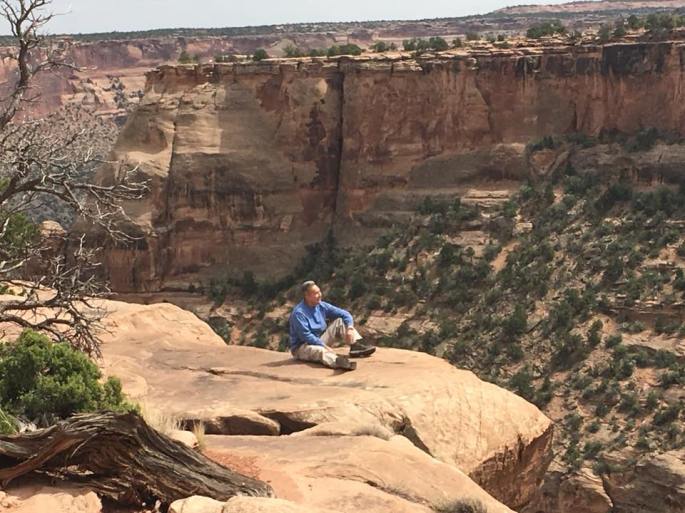 Michael sitting on rock ledge overlooking Monument Canyon
