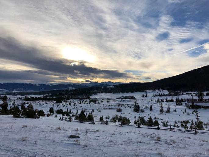 Early morning sunrise of a open field of snow and mountains in the background