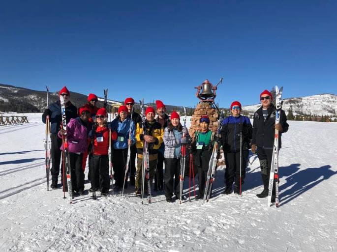 Team Texas holding their skis and poles taking their group photo out on the snow under bright blue skies